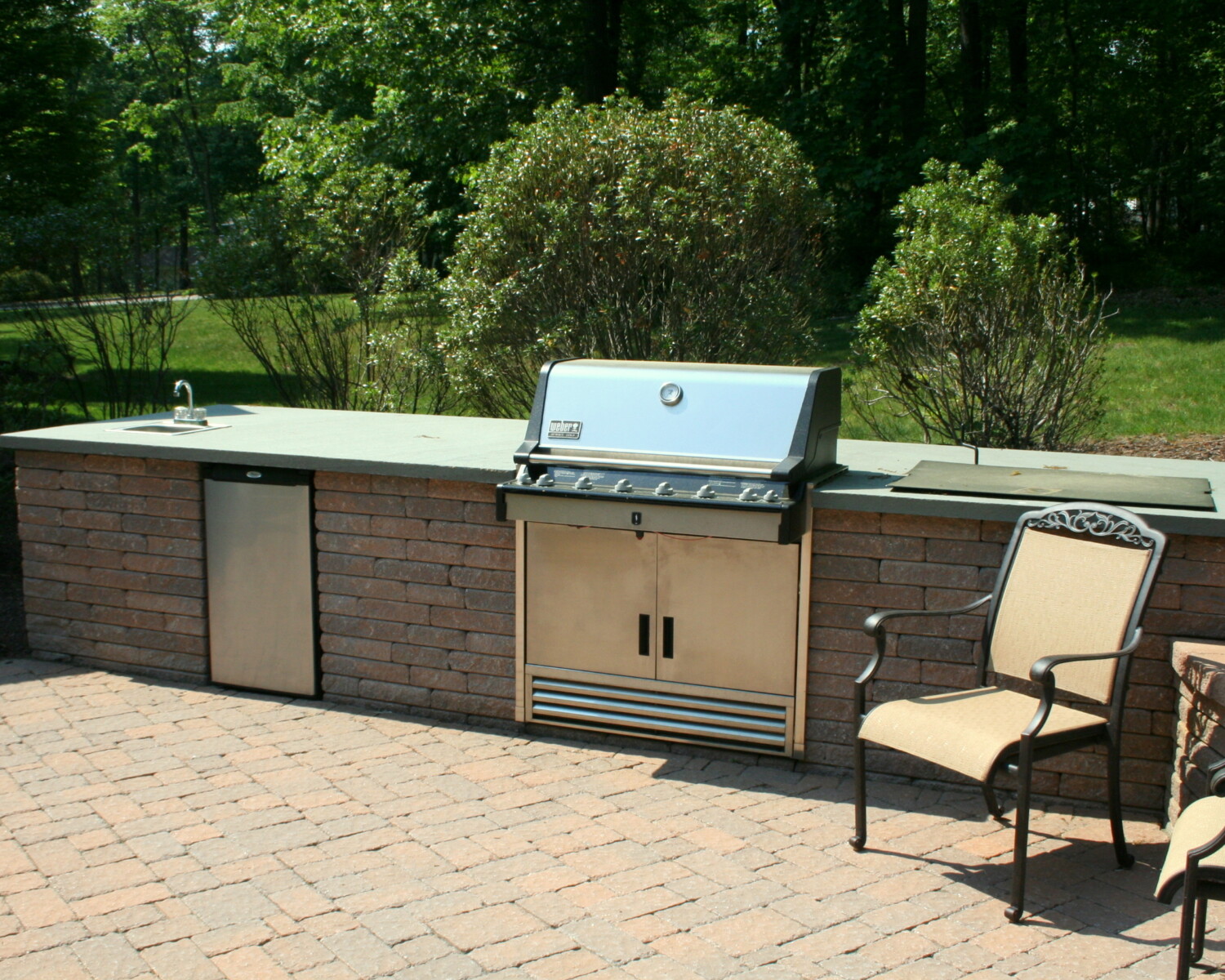 Outdoor grilling station includes a sink and refrigerator
