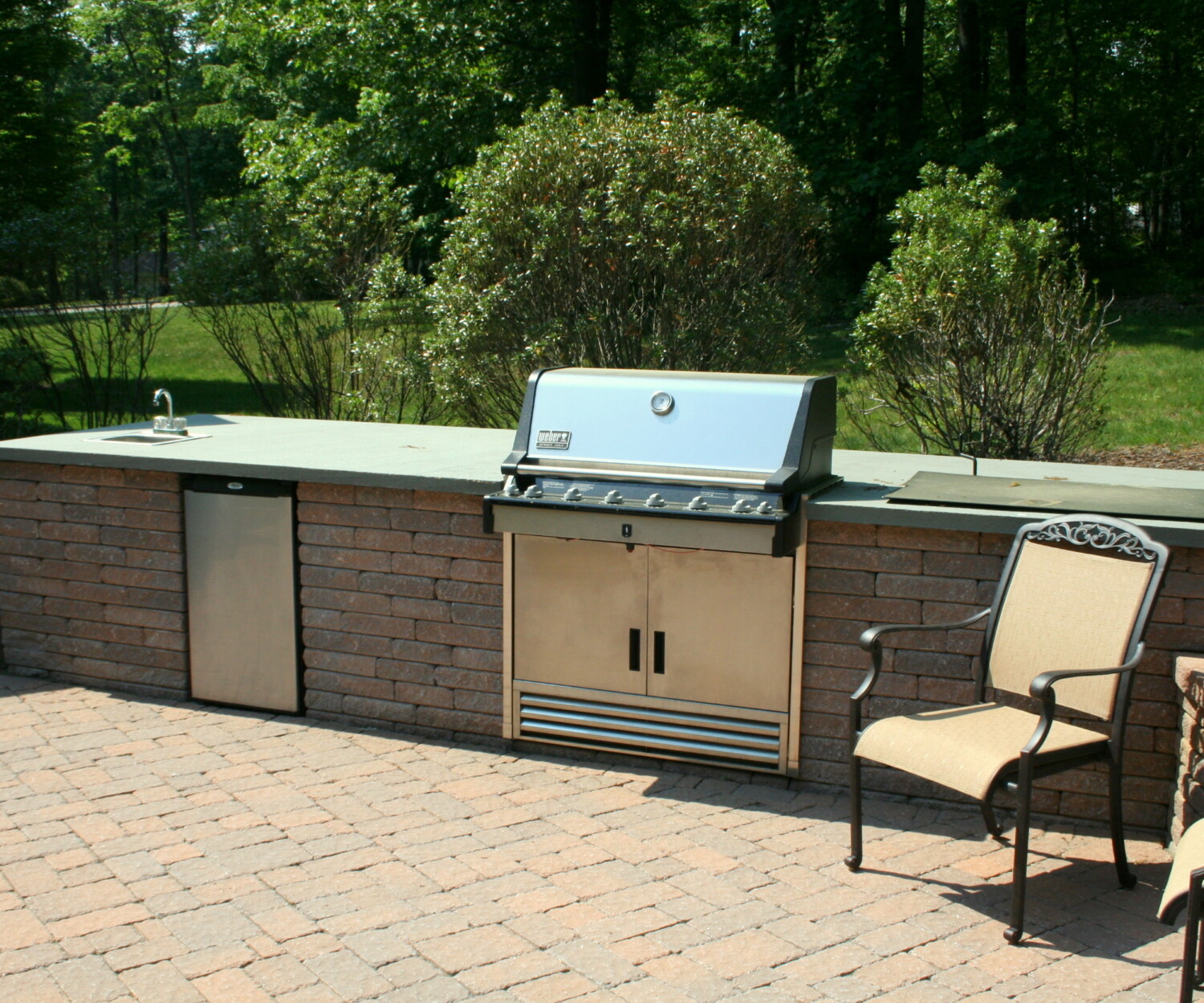 Outdoor grilling station includes a sink and refrigerator